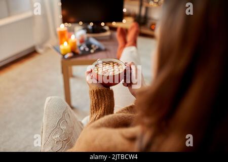 Frau schaut an halloween Fernsehen und trinkt Kakao Stockfoto