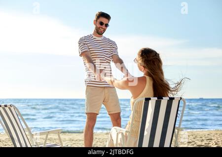 Glückliches Paar, das in Klappstühlen am Strand sitzt Stockfoto