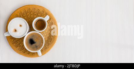 Drei Tassen Kaffee auf weißem Hintergrund, flach liegend. Stockfoto