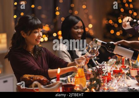 Glückliche Freunde trinken Wein auf der weihnachtsfeier Stockfoto