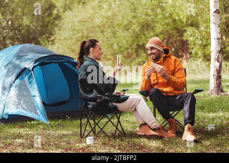 Glückliches Paar, das im Zeltlager Sandwiches isst Stockfoto