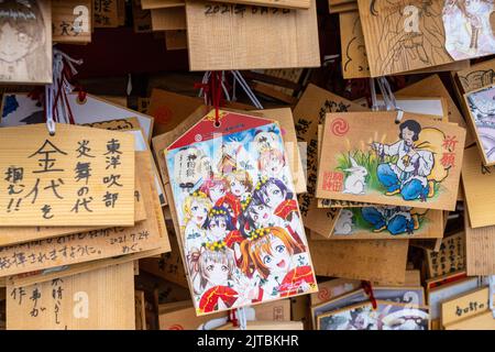 Japanische Anime- und Manga-Figuren, die auf ema-Gebetstafeln am Kanda Myojin-Schrein gemalt sind, einem schintoistischen Schrein, der Geschäftsreisenden und Technikbegeisterten in Chiyoda, Tokio, Japan, gewidmet ist. Die Gläubigen hängen die Tafeln mit ihren Wünschen, Träumen oder Gebeten im Tempel auf. Stockfoto