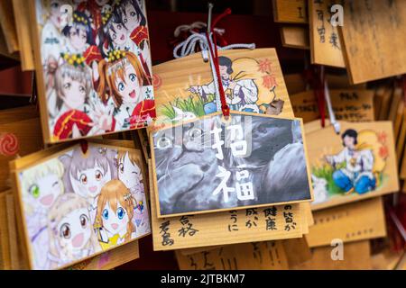 Japanische Anime- und Manga-Figuren, die auf ema-Gebetstafeln am Kanda Myojin-Schrein gemalt sind, einem schintoistischen Schrein, der Geschäftsreisenden und Technikbegeisterten in Chiyoda, Tokio, Japan, gewidmet ist. Die Gläubigen hängen die Tafeln mit ihren Wünschen, Träumen oder Gebeten im Tempel auf. Stockfoto