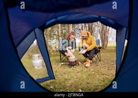 Paar kochen Essen auf einem Gasbrenner im Zeltlager Stockfoto