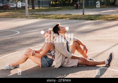 Pärchen sitzt auf dem Boden und bläst Blasengummis Stockfoto