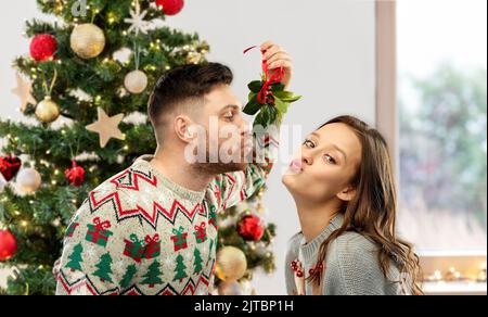 Pärchen küsst sich an weihnachten unter der Mistel Stockfoto