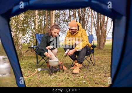 Paar kochen Essen auf einem Gasbrenner im Zeltlager Stockfoto