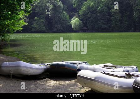 Schwarz-weiße Schlauchboote am Ufer des Sees Parz (klar), gegen den grünen Wald im Hintergrund, Dilijan, Armenien Stockfoto