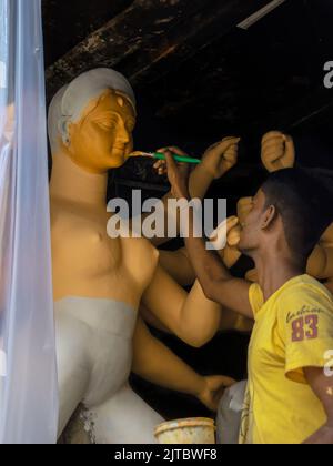 Kolkata, Indien - 28. August 2022: Ein Mann, der Farbe auf das Tonidol von Devi Durga für das kommende Durga Puja Festival legt. Selektiver Fokus auf das Gesicht des Idols Stockfoto