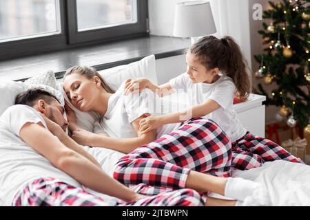 Glückliches Mädchen weckt ihre Eltern am weihnachtsmorgen Stockfoto