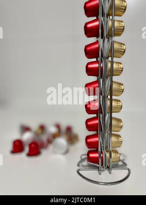 Eine vertikale Nahaufnahme von roten und goldenen Kaffeekapseln auf einer weißen Oberfläche Stockfoto