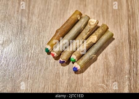 HANDGEMACHTE RUSTIKALE BUNTSTIFTE ÜBER EINEM HOLZTISCH. AUS NATÜRLICHEM HOLZSTAMM. DRAUFSICHT Stockfoto