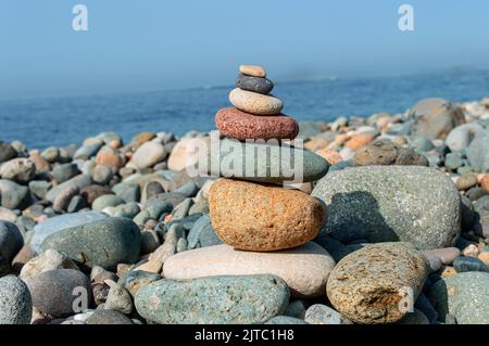 Bunte Steine sind natürlich ausgeglichen auf dem Hintergrund des Meeres. Stockfoto
