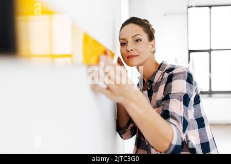 Glückliche Frau mit einer waage messenden Wand zu Hause Stockfoto
