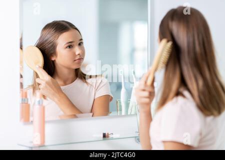 Teenager-Mädchen putzt Haare mit Kamm im Badezimmer Stockfoto