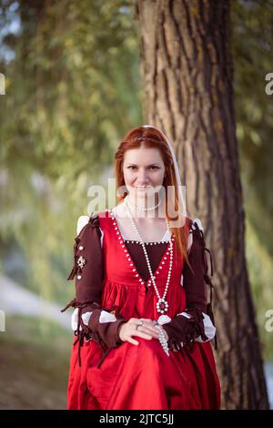 Rothaarige schlanke Mädchen in einem roten Kleid in der venezianischen Mode des 15.. Jahrhunderts, halblanges Porträt Stockfoto