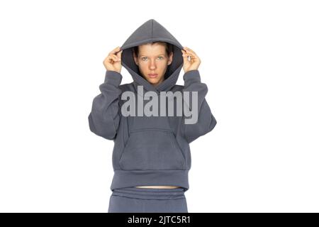 Mädchen in einem warmen grauen Sportanzug auf weißem Hintergrund, Sweatshirt und Sporthosen, Damenbekleidung, Mode Stockfoto