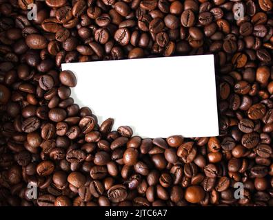 Leere weiße Karte für Ihren Text auf Kaffeebohnen Hintergrund Nahaufnahme Foto Stockfoto