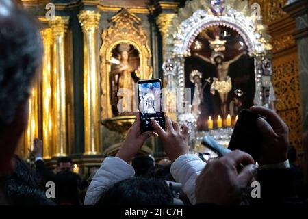 Eifrige Anhänger, die Fotos vom Hauptaltar und Prozessionsbild mit ihren Mobiltelefonen in der Kirche von Las Nazarenas machen - Herr der Wunder. Stockfoto