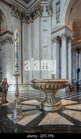 London, England, Großbritannien - 6. Juli 2022: St. Paul's Cathedral. Großes Taufbecken aus Marmor mit hoher Kerze in silbernem Halter, beide stehen auf gefliestem Marmor Stockfoto