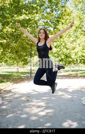 Glückliche Frau, die beim Training auf der Straße springt Stockfoto