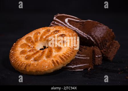 In Scheiben geschnittene Schokoladenkekse Rolle mit Schokoladenkeksen auf schwarzem Hintergrund. Stockfoto