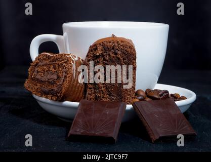 Ein Stück hausgemachte Biskuitrolle. Im Hintergrund ist ein weißer Becher Stockfoto