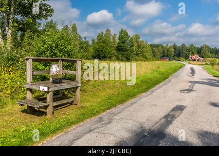 Podest an der Straße, auf der Milchdosen stehen. In der Vergangenheit kam der Milchwagen zweimal täglich vorbei, um die frische Milch abzuholen. Ulricehamns kommun, Schweden Stockfoto