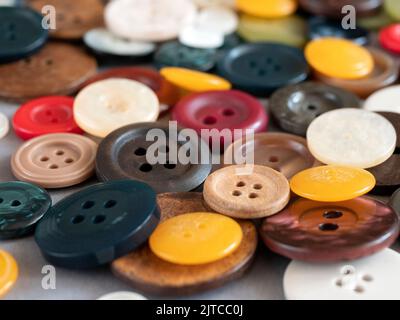 Runde Näh-Knöpfe in verschiedenen Farben und Größen, Nahaufnahme. Verschiedene farbige flache Tasten mit zwei oder vier Löchern, selektiver Fokus Stockfoto