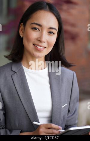 Lächelnde junge asiatische Frau Unternehmerin trägt Anzug, vertikale Headshot Porträt. Stockfoto