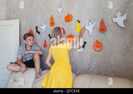 Kinder hängen eine Girlande für die Halloween Party an die Wand. Stockfoto