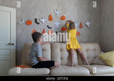 Kinder hängen eine Girlande für die Halloween Party an die Wand. Stockfoto