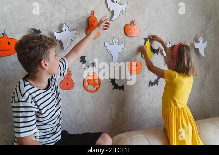 Kinder hängen eine Girlande für die Halloween Party an die Wand. Stockfoto