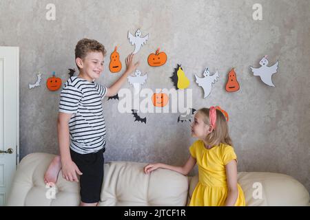 Kinder hängen eine Girlande für die Halloween Party an die Wand. Stockfoto