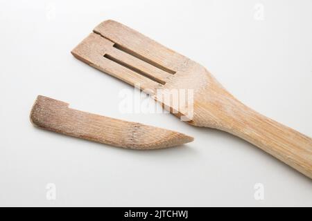Eine Nahaufnahme eines gebrauchten Holzspatels, der auf einem neutralweißen Hintergrund an seinem schwächsten Teil eingerastet ist Stockfoto