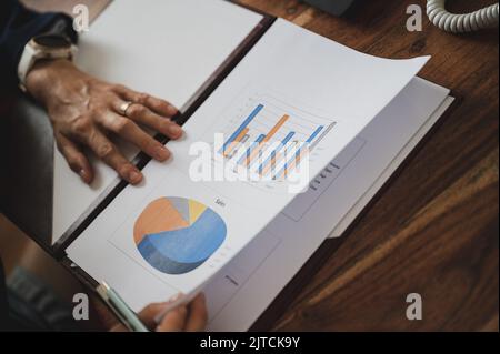 Nahaufnahme einer Geschäftsfrau, Unternehmerin, Überprüfung des jährlichen Verkaufsberichts mit Grafiken und Diagrammen. Stockfoto