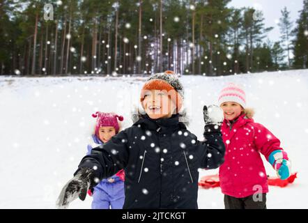 Glückliche kleine Kinder spielen Schneeballschlacht im Winter Stockfoto