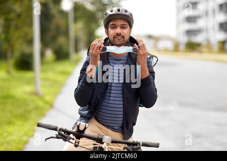 Lieferung Mann in Maske mit smatphone Fahrrad fahren Stockfoto