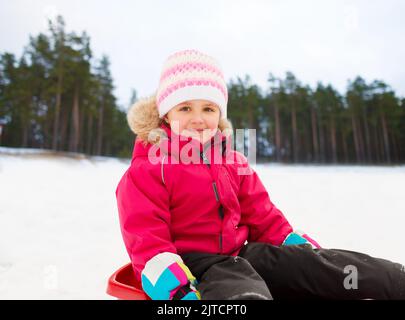 Glückliche kleine Mädchen auf Schlitten im Winter Stockfoto