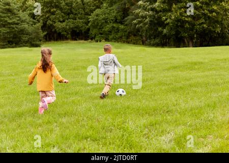 Kleine Kinder mit Ball spielen Fußball im Park Stockfoto