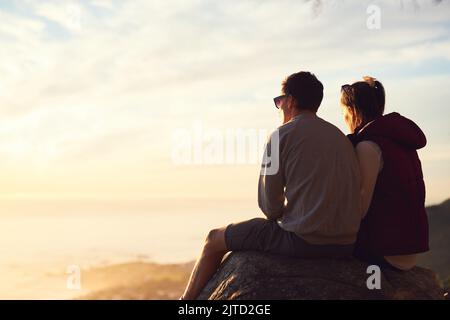 Abmelden für das Wochenende. Rückansicht eines jungen Paares, das die Aussicht von der Spitze eines Berges bewundert. Stockfoto