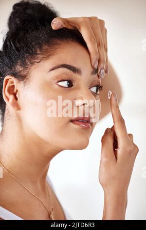 Ihre Augen und ihr Sehvermögen in Höchstleistung und Gesundheit halten. Eine junge Frau, die zu Hause Kontaktlinsen einbringt. Stockfoto