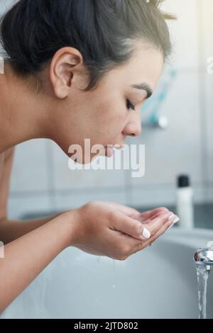 Wunder für ihre Haut durch eine konsequente Hautpflege Routine. Eine attraktive junge Frau waschen ihr Gesicht im Badezimmer. Stockfoto