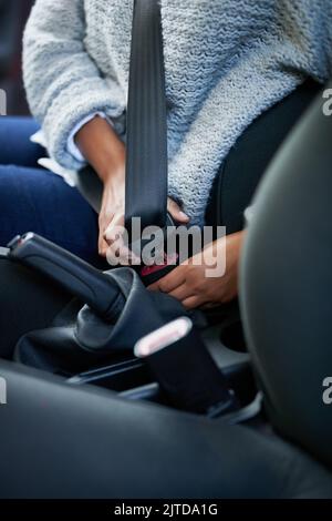 Sicherheit steht an erster Stelle. Nahaufnahme einer Frau, die ihren Sicherheitsgurt in einem Auto befestigt. Stockfoto