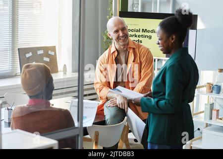 Vielfältige Gruppe von kreativen erwachsenen Menschen diskutieren Arbeitsprojekt im Büro und lächeln Stockfoto