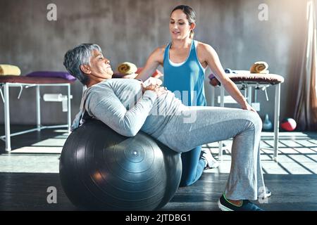 Die älteren Jahre müssen nicht die sitzenden Jahre sein. Eine ältere Frau, die mit ihrem Physiotherapeuten arbeitet. Stockfoto