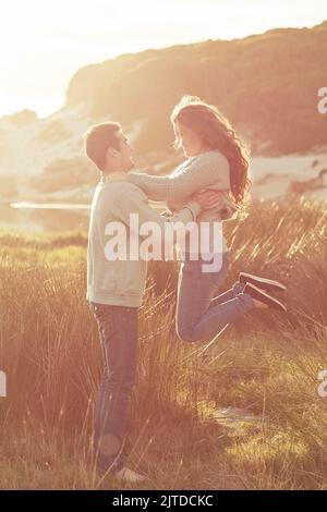 Höher gehoben von seiner Liebe. Ein junges Paar, das am Wochenende gemeinsam am Strand relaxt. Stockfoto