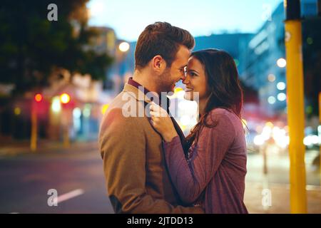 Ein liebevolles junges Paar, das sich bei einem Date in der Stadt küsst. Stockfoto