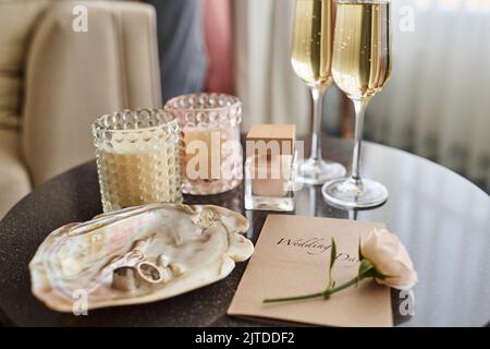 Champagner-Flöten, eine Flasche Duft, Hochzeitseinladung mit weißer Rose und zwei Gläsern Cocktail schaffen eine romantische Komposition Stockfoto