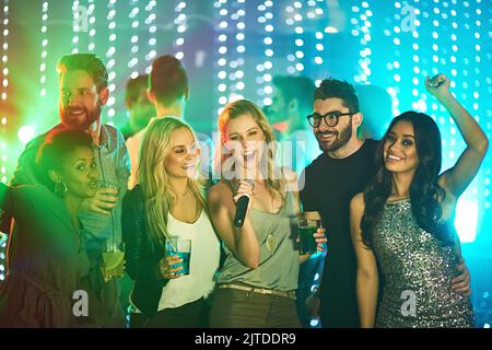 Diese geht zu meinen Freunden. Eine Gruppe von Freunden singt Karaoke auf einer Party. Stockfoto